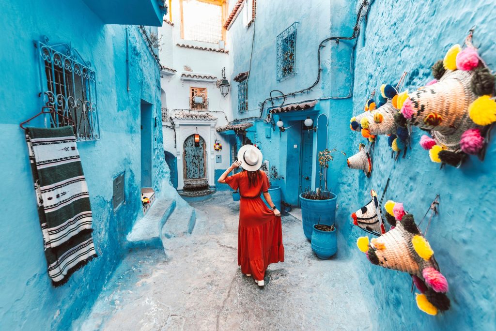 Young woman with red dress visiting the blue city Chefchaouen, Marocco