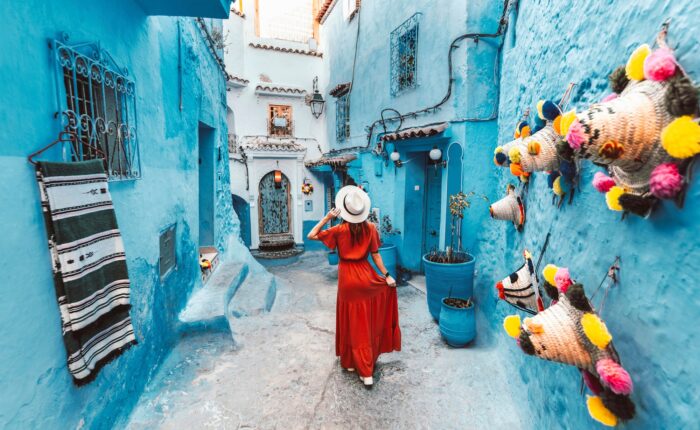 Young woman with red dress visiting the blue city Chefchaouen, Marocco