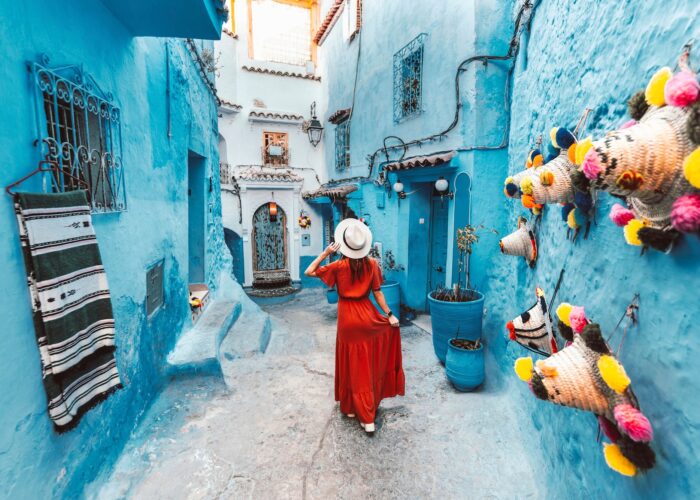 Young woman with red dress visiting the blue city Chefchaouen, Marocco